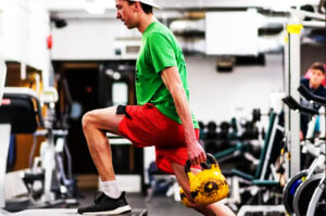 Image of an athlete doing a kettlebell step up and the Saltus Performance gym