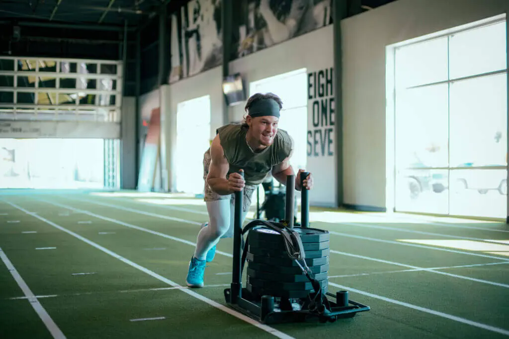 A man pushing a weighted sled for the purpose of strength training for baseball
