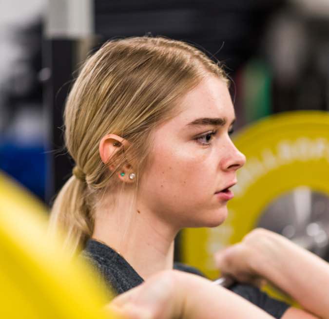 A girl who is doing a front squat with a barbell