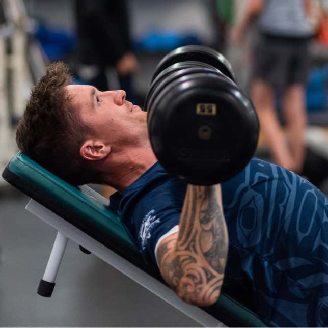 A image of a man doing a dumbell press